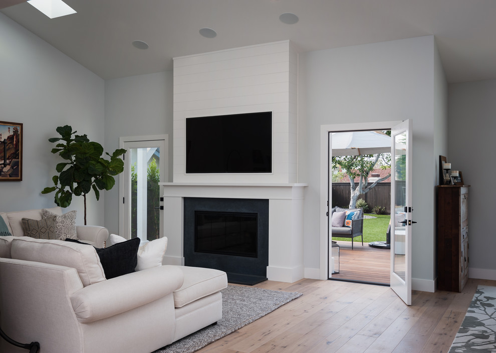 Modernes Wohnzimmer mit weißer Wandfarbe, braunem Holzboden, Kamin, Kaminumrandung aus Holz, Multimediawand und braunem Boden in San Diego