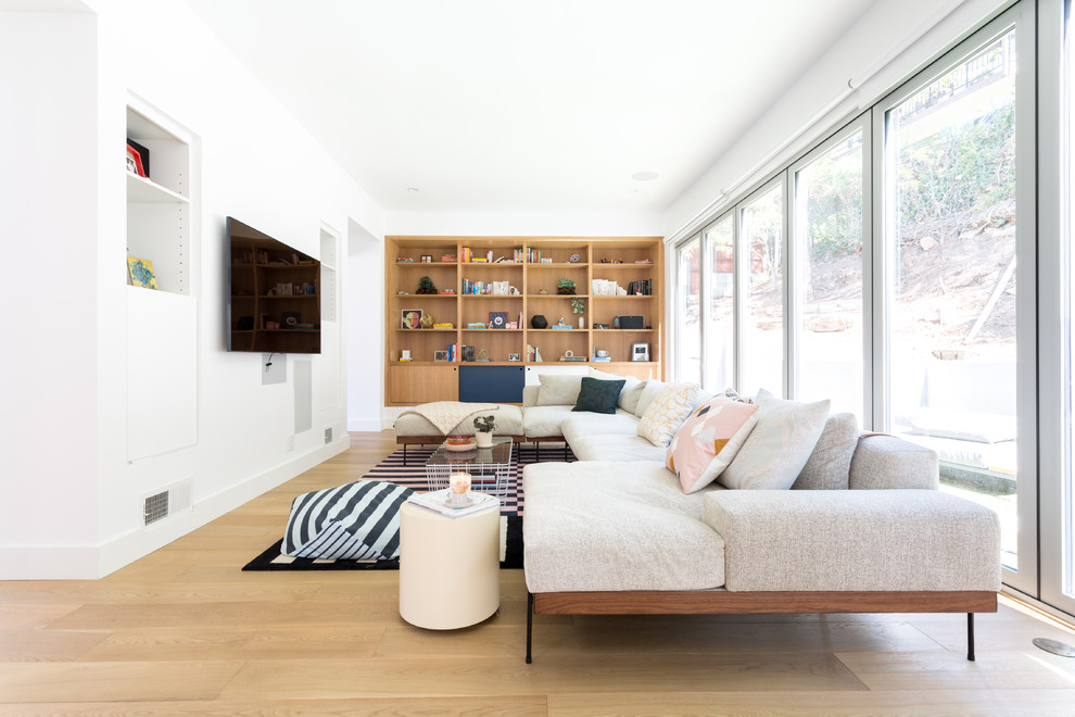 Idee per un grande soggiorno design aperto con pareti bianche, TV a parete, pavimento in legno massello medio e pavimento marrone