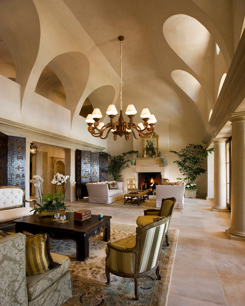 Стильный дизайн: огромная парадная, открытая гостиная комната в средиземноморском стиле с бежевыми стенами, стандартным камином, полом из травертина и фасадом камина из камня без телевизора - последний тренд