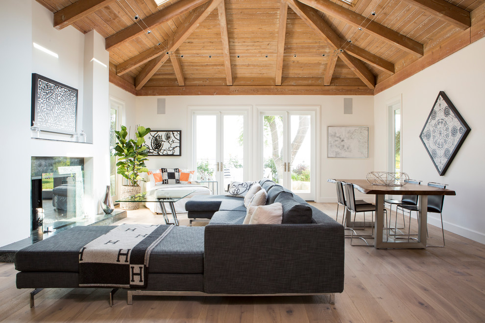 Immagine di un ampio soggiorno stile marino aperto con pareti bianche, camino classico, parquet chiaro e pavimento marrone