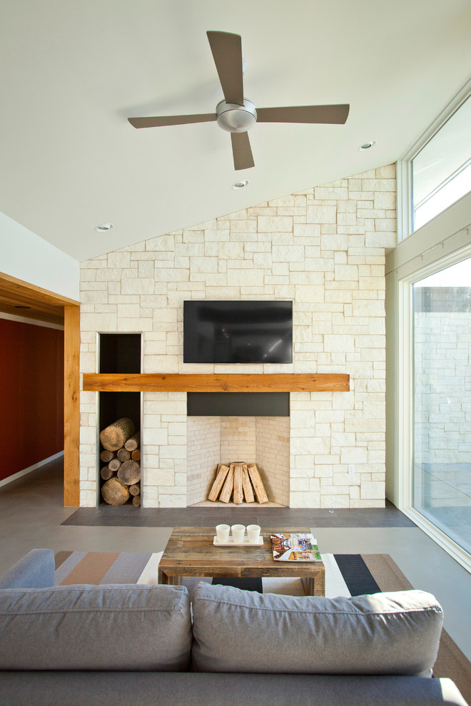 Immagine di un soggiorno minimalista con camino classico e TV a parete