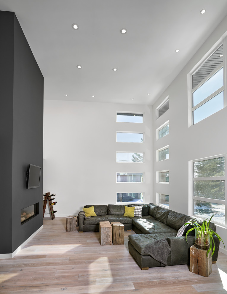 Idée de décoration pour un grand salon design avec un mur gris et parquet clair.