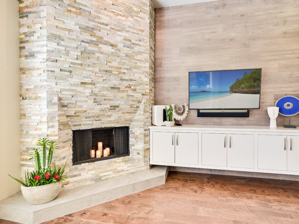Пример оригинального дизайна: открытая гостиная комната среднего размера в стиле модернизм с бежевыми стенами, паркетным полом среднего тона, угловым камином, фасадом камина из камня, телевизором на стене и коричневым полом