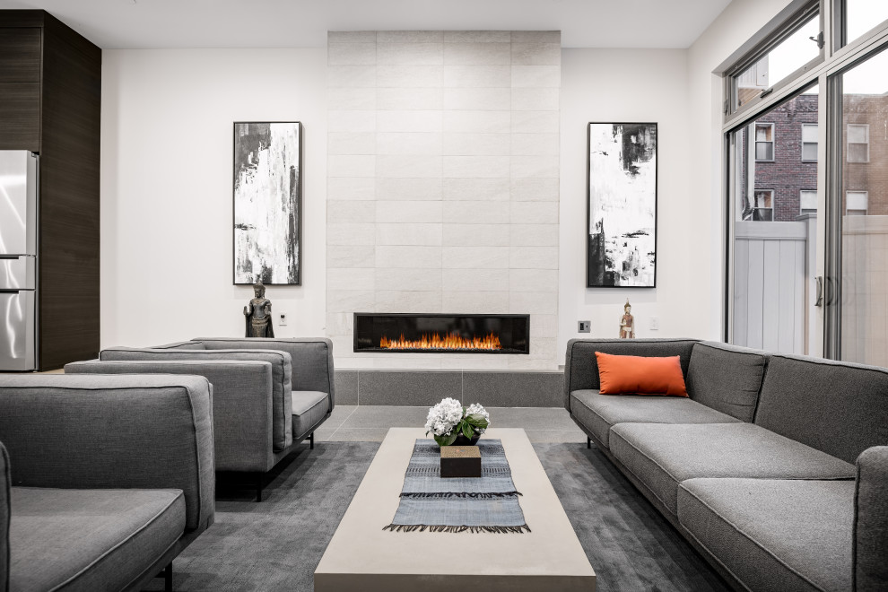 Modern open plan living room in Philadelphia with white walls, porcelain flooring, a ribbon fireplace, a tiled fireplace surround and grey floors.