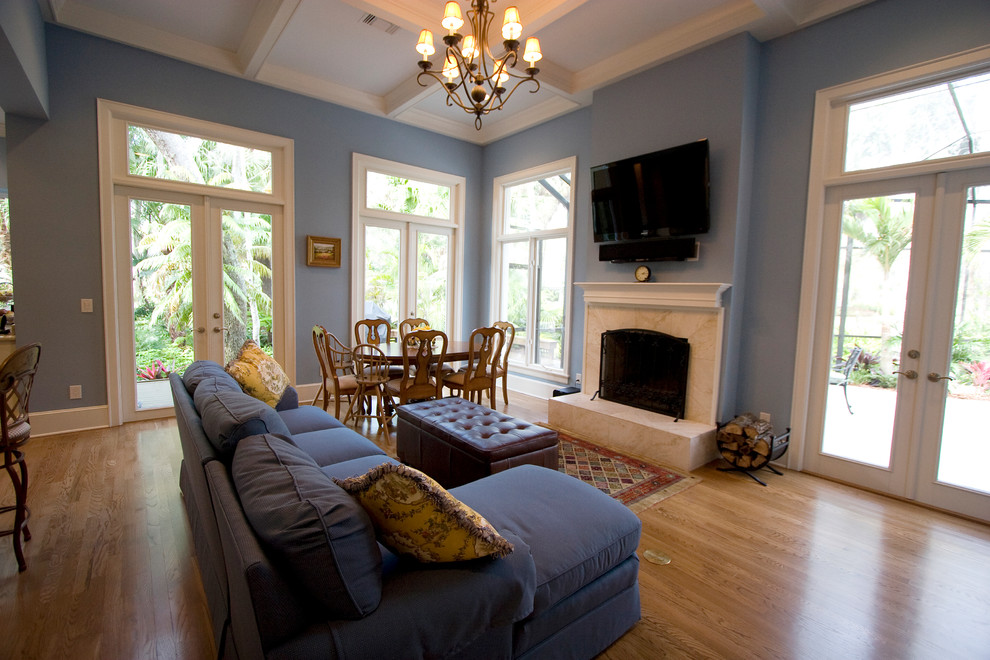 Idee per un soggiorno tradizionale di medie dimensioni e aperto con pareti blu, parquet chiaro, camino classico, cornice del camino in intonaco e TV a parete