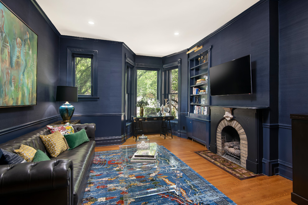 Cette photo montre un salon chic avec un mur bleu, un sol en bois brun, une cheminée standard, un téléviseur fixé au mur et un sol marron.