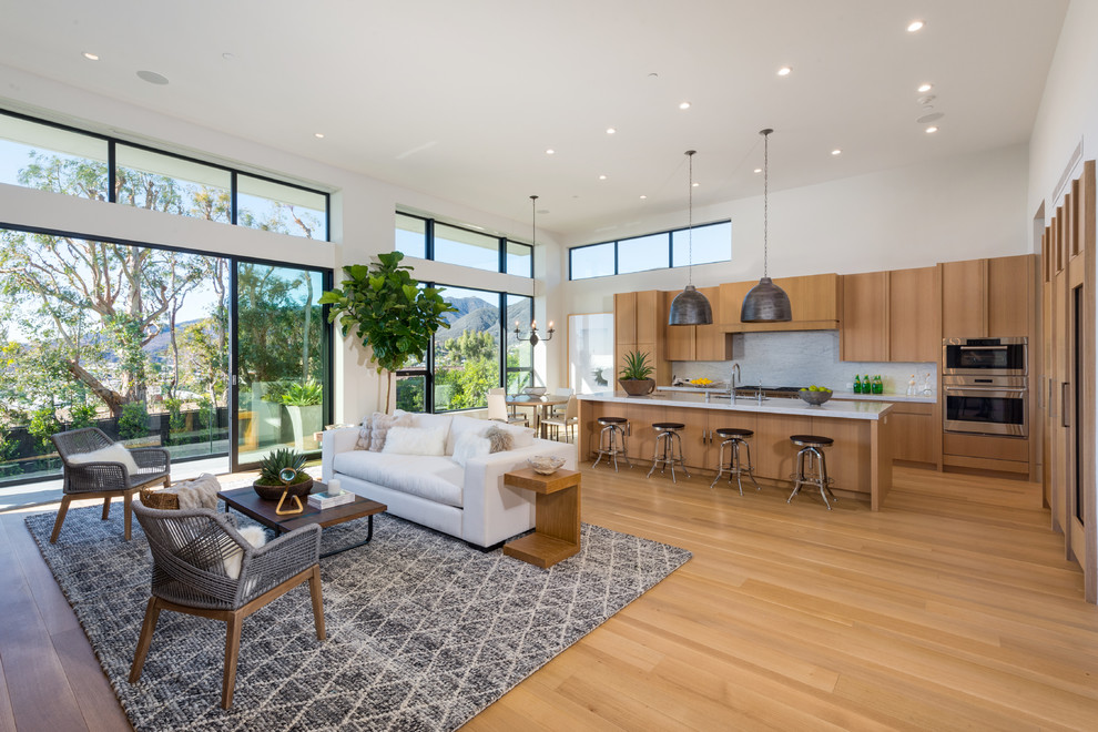 Großes, Offenes Modernes Wohnzimmer mit weißer Wandfarbe, hellem Holzboden, Gaskamin und Kaminumrandung aus Stein in Los Angeles