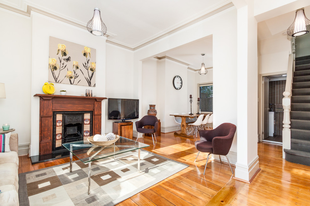 Offenes Modernes Wohnzimmer mit beiger Wandfarbe, braunem Holzboden, Kamin und freistehendem TV in Sydney