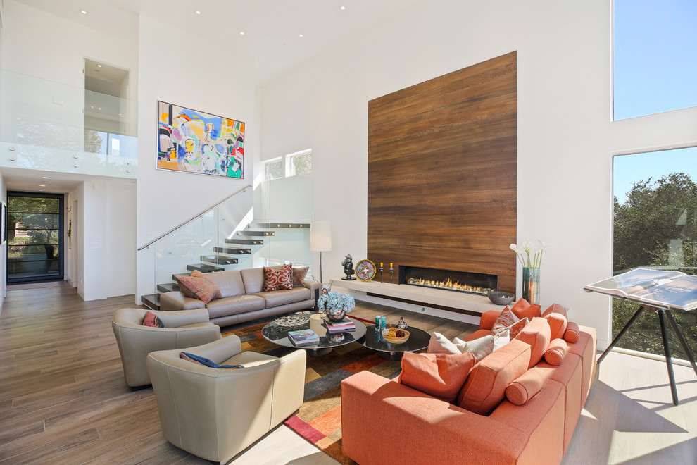 Offenes Modernes Wohnzimmer mit weißer Wandfarbe, braunem Holzboden, Gaskamin, Kaminumrandung aus Holz und braunem Boden in San Francisco