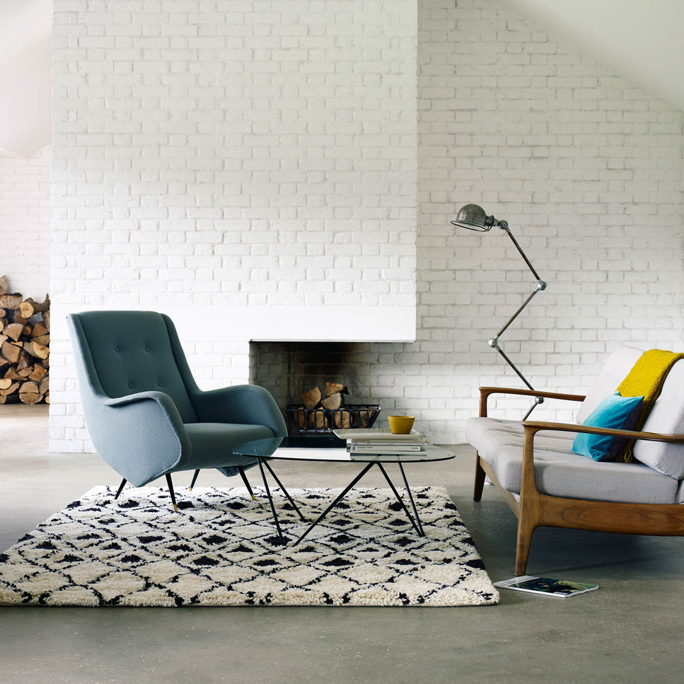 Ispirazione per un soggiorno minimal con pareti bianche, pavimento in cemento, camino classico e cornice del camino in mattoni