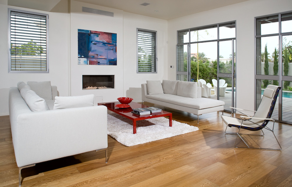 Diseño de salón moderno con paredes blancas, suelo de madera en tonos medios y chimenea lineal