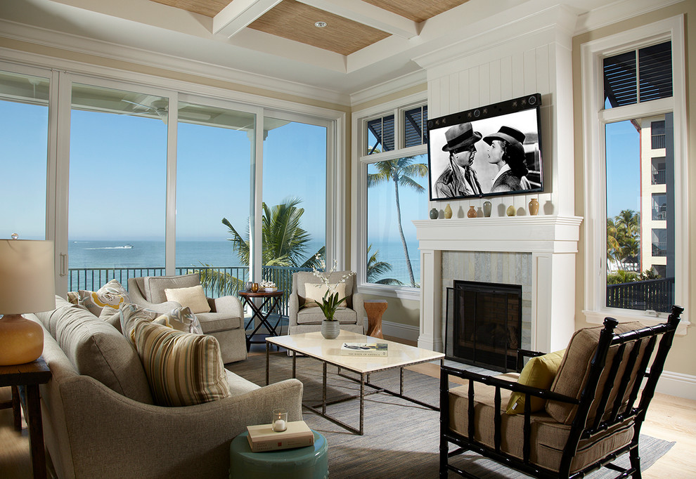 マイアミにあるビーチスタイルのおしゃれな応接間 (ベージュの壁、標準型暖炉、タイルの暖炉まわり、壁掛け型テレビ) の写真
