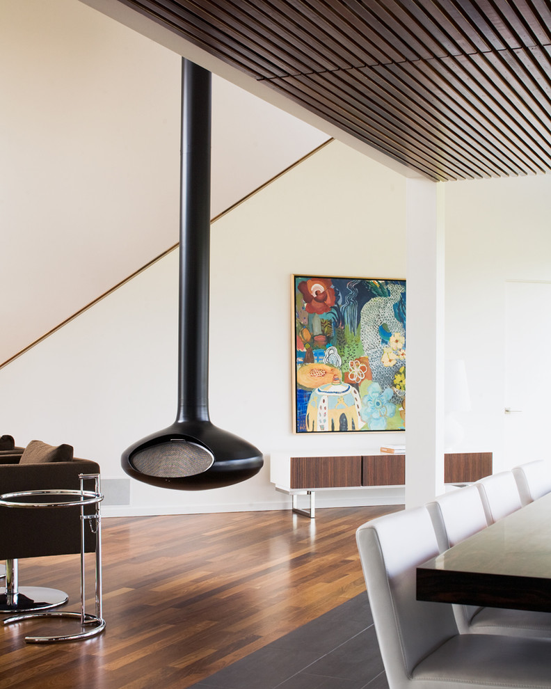 На фото: гостиная комната в стиле модернизм с белыми стенами и подвесным камином с