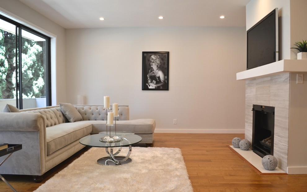 Photo of a small modern open plan living room in Los Angeles with grey walls, medium hardwood flooring, a standard fireplace, a tiled fireplace surround and a wall mounted tv.