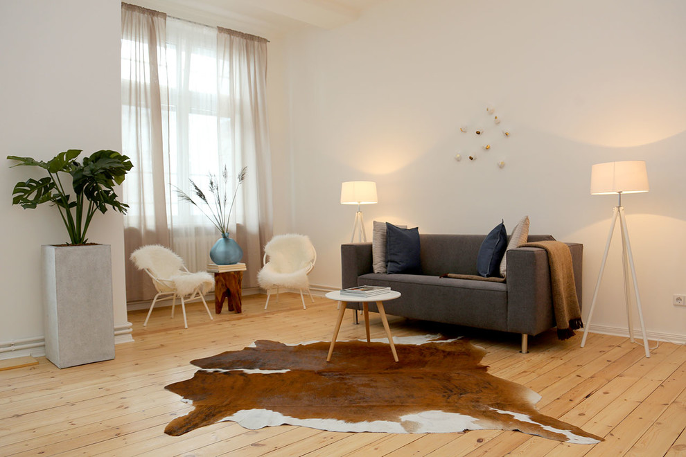 Mittelgroßes, Abgetrenntes Skandinavisches Wohnzimmer ohne Kamin mit weißer Wandfarbe und hellem Holzboden in Berlin