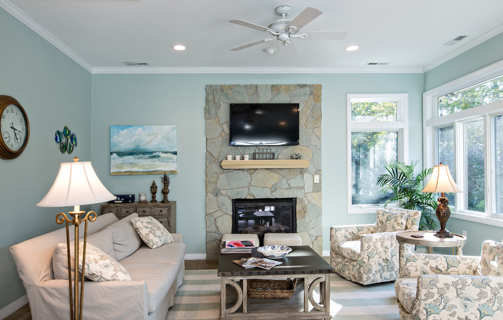 Mittelgroßes, Offenes Maritimes Wohnzimmer mit blauer Wandfarbe, hellem Holzboden, Kamin, Kaminumrandung aus Stein und TV-Wand in Sonstige