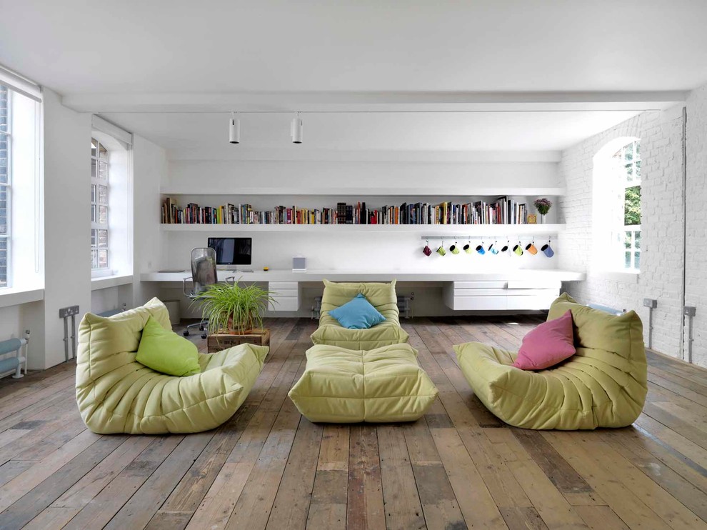 Idee per un soggiorno industriale aperto con libreria, pareti bianche e pavimento in legno massello medio