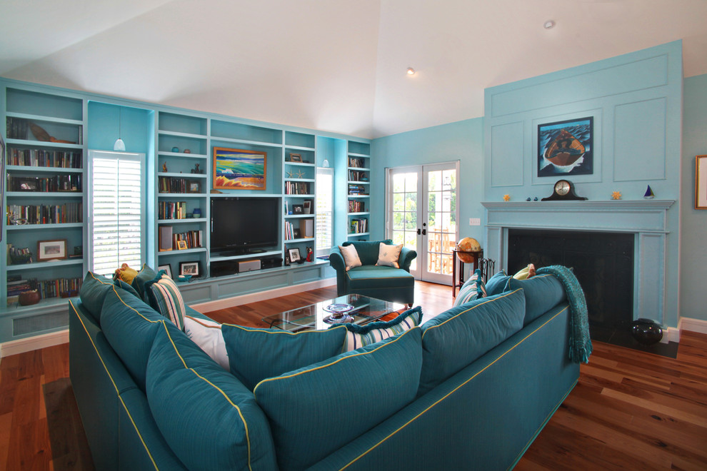 На фото: гостиная комната в морском стиле с синими стенами, стандартным камином, отдельно стоящим телевизором и синим диваном