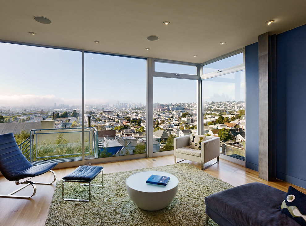 Стильный дизайн: гостиная комната в стиле модернизм с синими стенами, паркетным полом среднего тона и акцентной стеной - последний тренд