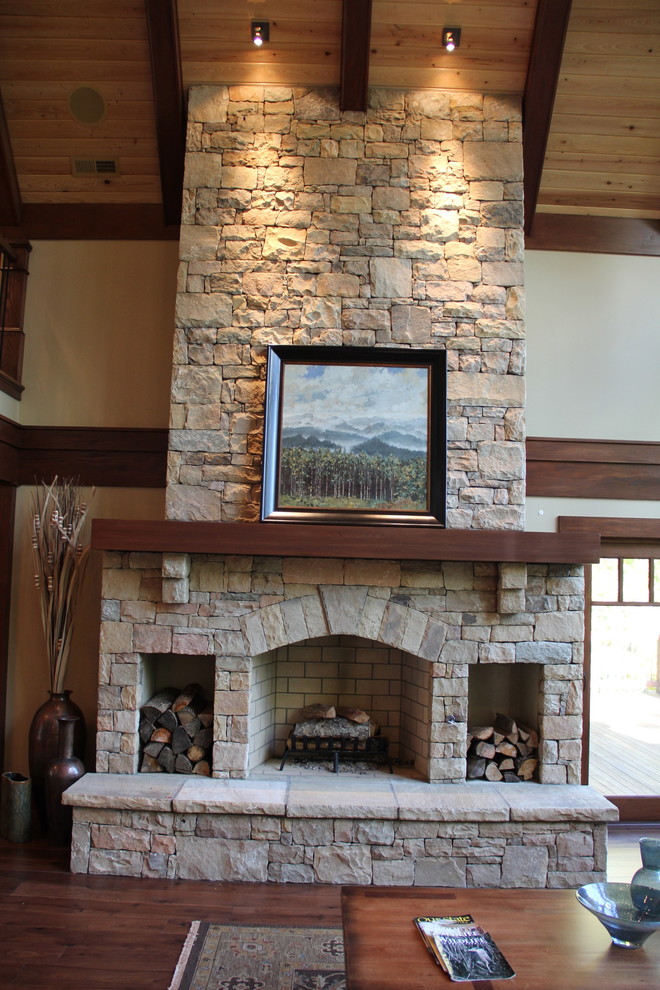 Exemple d'un salon craftsman ouvert avec une salle de réception, parquet foncé, une cheminée standard et un manteau de cheminée en pierre.