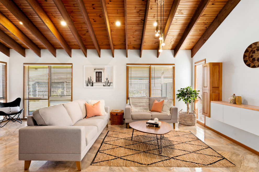 Пример оригинального дизайна: гостиная комната в морском стиле с белыми стенами, коричневым полом, балками на потолке, сводчатым потолком и деревянным потолком