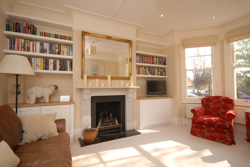 Photo of a medium sized classic enclosed living room in London with beige walls, carpet, a standard fireplace, a stone fireplace surround and a freestanding tv.