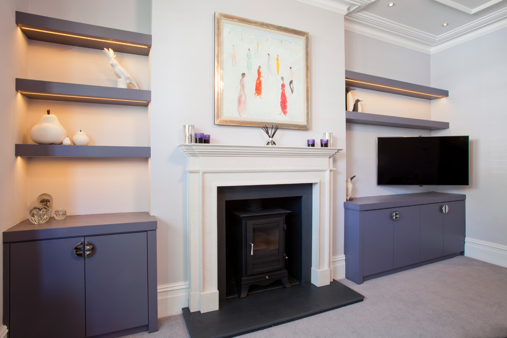 Mittelgroßes, Abgetrenntes Klassisches Wohnzimmer mit weißer Wandfarbe, Teppichboden, Kaminofen, Kaminumrandung aus Stein und TV-Wand in London