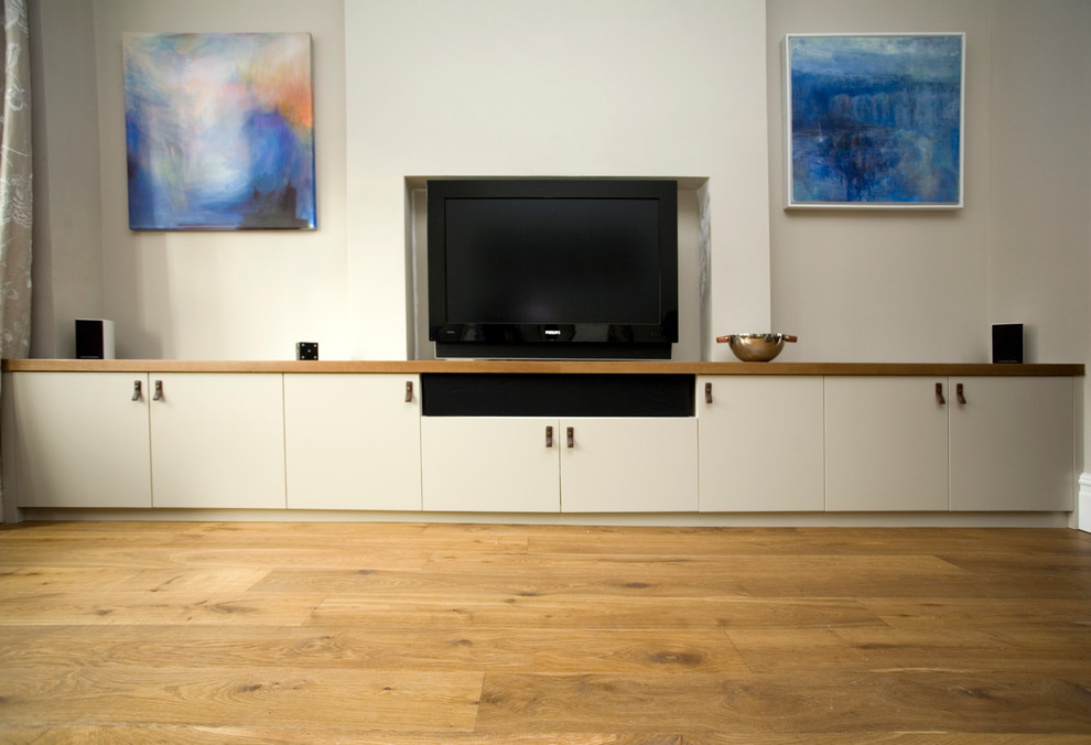 Large minimalist enclosed medium tone wood floor living room photo in London with white walls, no fireplace and a media wall