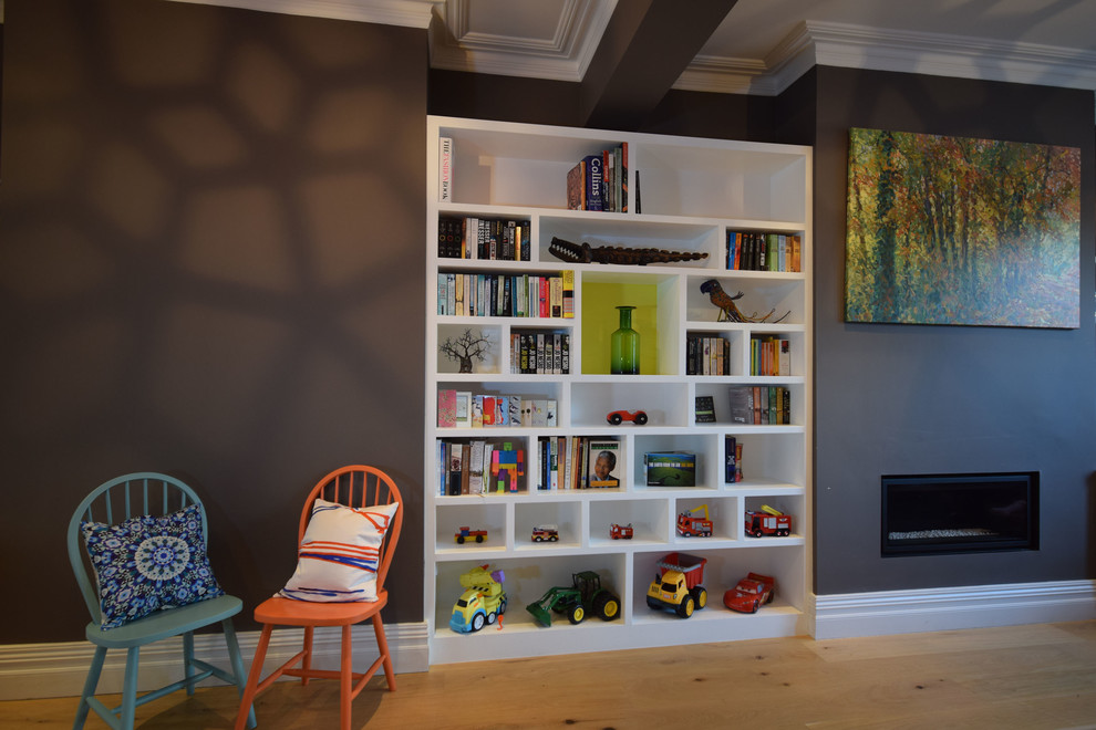 Idée de décoration pour un salon design de taille moyenne avec une bibliothèque ou un coin lecture, un mur gris, parquet clair, une cheminée ribbon et un sol marron.