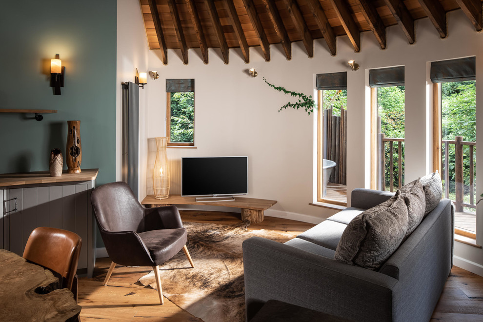 Kleines Uriges Wohnzimmer ohne Kamin mit weißer Wandfarbe, braunem Holzboden, freistehendem TV und beigem Boden in Cornwall