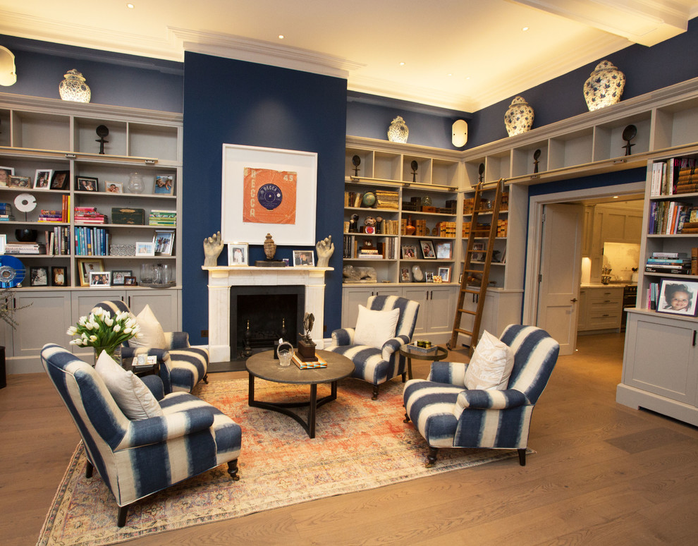 Example of a mid-sized classic open concept dark wood floor and brown floor living room library design in London with blue walls, a standard fireplace and a stone fireplace