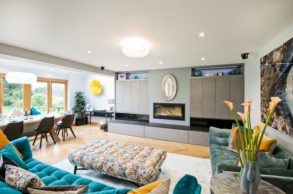 Inspiration for a contemporary open concept light wood floor living room remodel in West Midlands with a ribbon fireplace