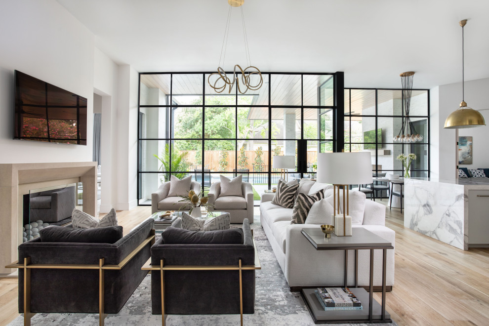 Photo of an expansive traditional open plan living room in Houston with white walls, light hardwood flooring, a standard fireplace, a wall mounted tv and brown floors.