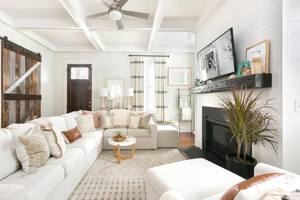 Wohnzimmer mit weißer Wandfarbe, braunem Holzboden, Kamin, TV-Wand und braunem Boden in Charleston