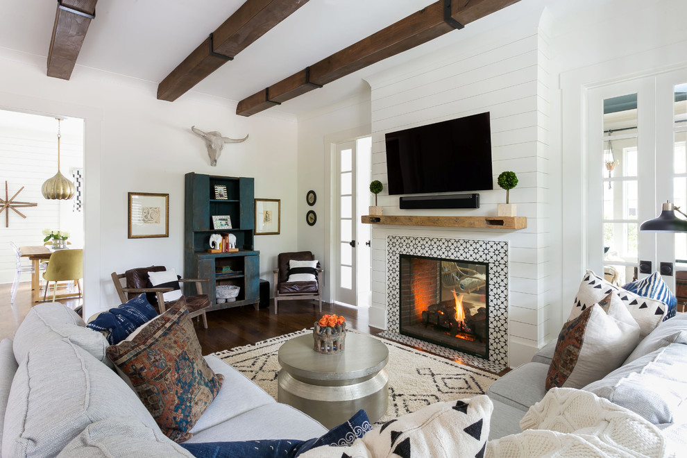 Maritimes Wohnzimmer mit weißer Wandfarbe, dunklem Holzboden, Tunnelkamin, gefliester Kaminumrandung, TV-Wand und braunem Boden in Charleston