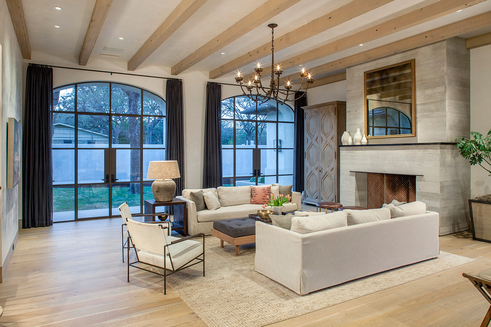 Großes, Offenes Mediterranes Wohnzimmer mit weißer Wandfarbe, hellem Holzboden, Kamin und Kaminumrandung aus Beton in Austin