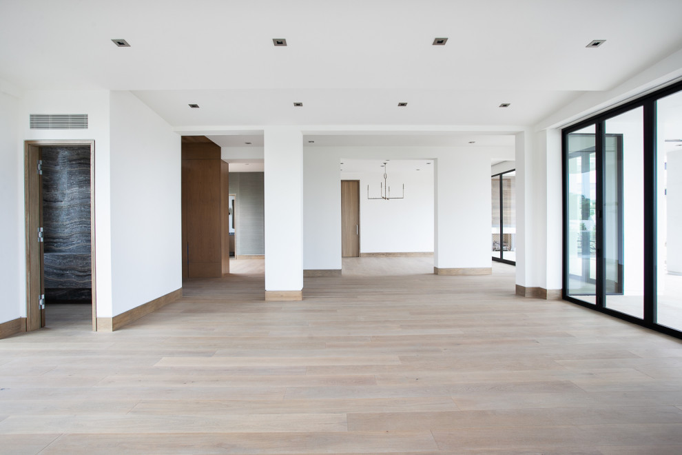 Modelo de salón para visitas abierto contemporáneo grande con paredes blancas y suelo de madera clara