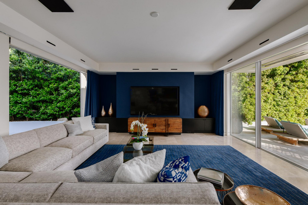 Пример оригинального дизайна: большая открытая гостиная комната в современном стиле с синими стенами, телевизором на стене и бежевым полом