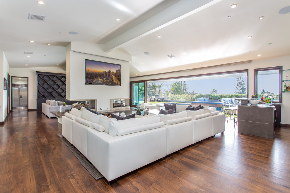 Mittelgroßes, Repräsentatives, Abgetrenntes Modernes Wohnzimmer mit weißer Wandfarbe, braunem Holzboden, Tunnelkamin, Kaminumrandung aus Metall, Multimediawand und braunem Boden in Los Angeles