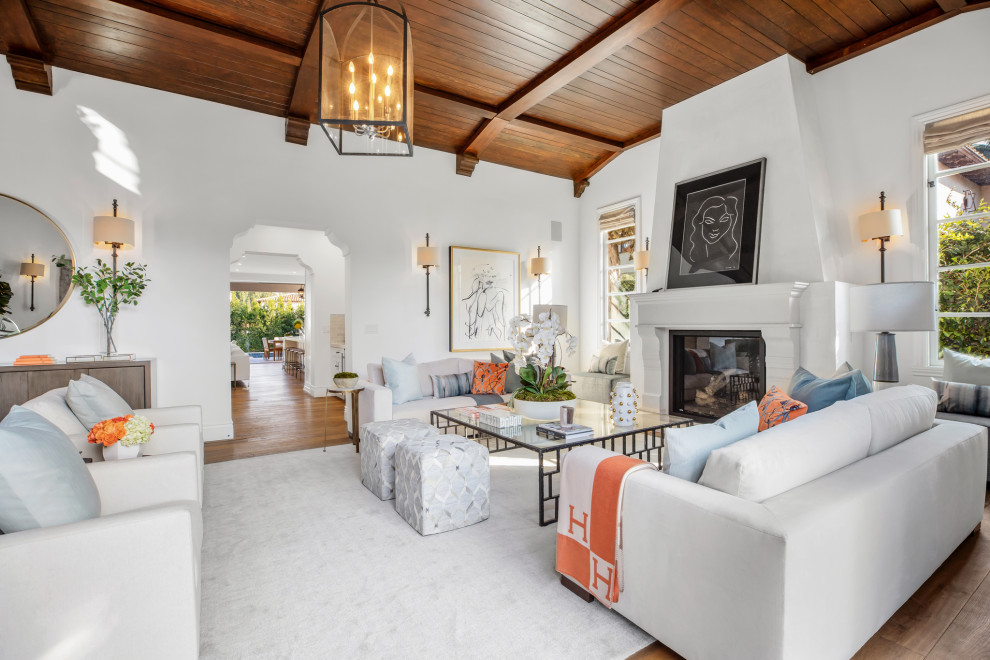 Repräsentatives, Fernseherloses, Abgetrenntes Mediterranes Wohnzimmer mit weißer Wandfarbe, braunem Holzboden, Kamin und Holzdecke in Los Angeles