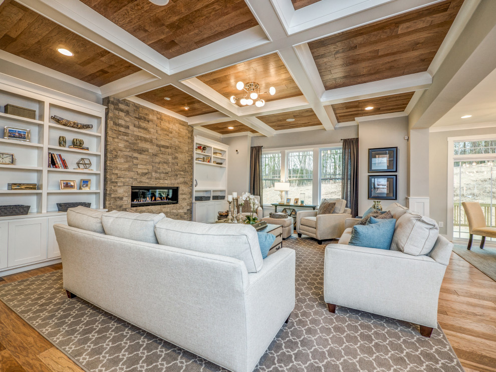 Inspiration for a huge open concept medium tone wood floor and coffered ceiling living room remodel in Charlotte with a ribbon fireplace and a stacked stone fireplace