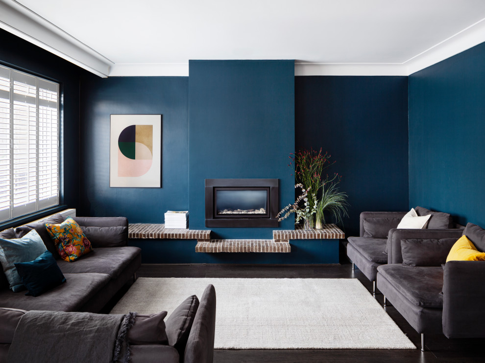 Ispirazione per un soggiorno minimal con pareti blu, parquet scuro, camino classico e pavimento marrone