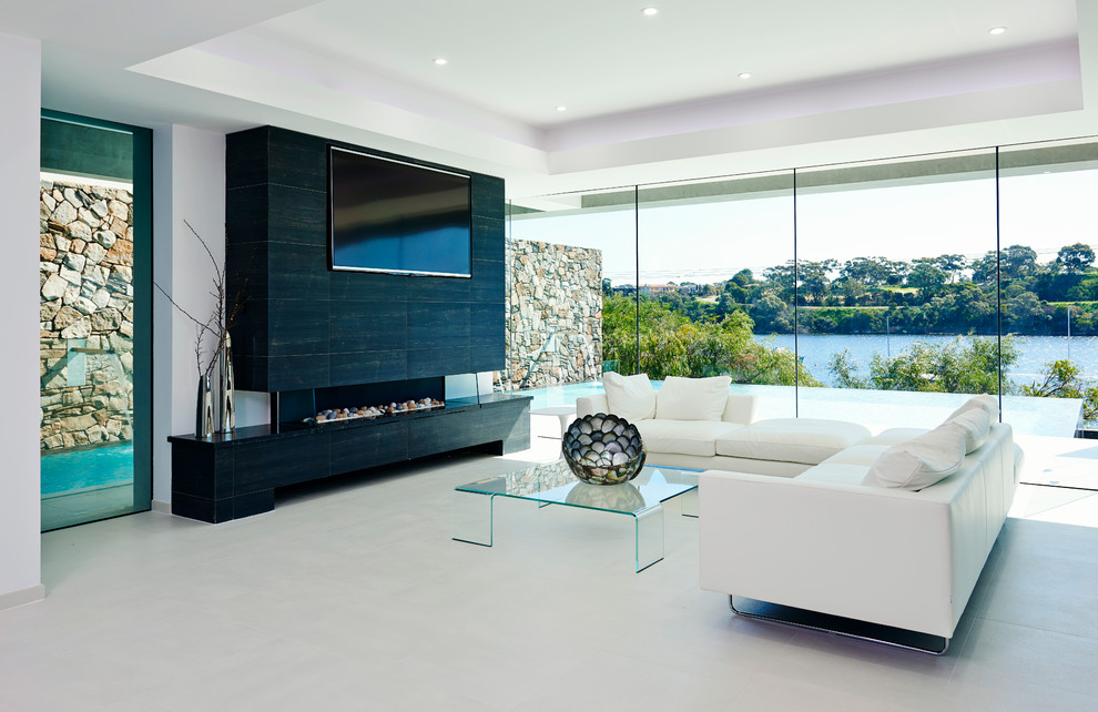 На фото: открытая гостиная комната среднего размера в современном стиле с горизонтальным камином, телевизором на стене и белыми стенами с