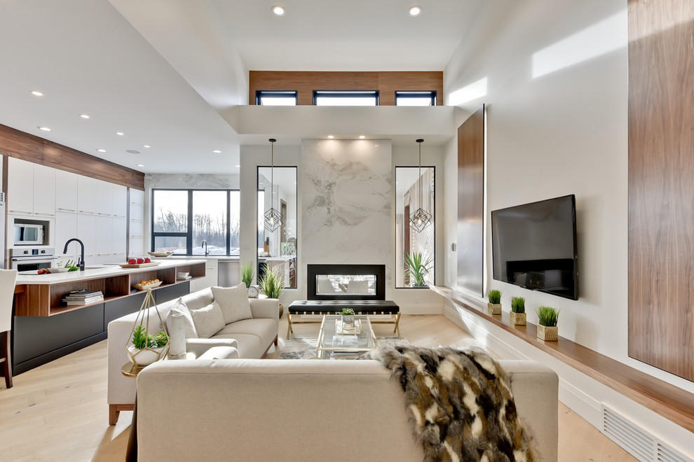 Großes, Offenes Modernes Wohnzimmer mit weißer Wandfarbe, hellem Holzboden, Tunnelkamin, TV-Wand und beigem Boden in Edmonton