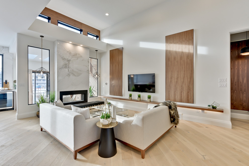 Photo of a large contemporary open plan living room in Edmonton with white walls, light hardwood flooring, a two-sided fireplace, a stone fireplace surround and a wall mounted tv.