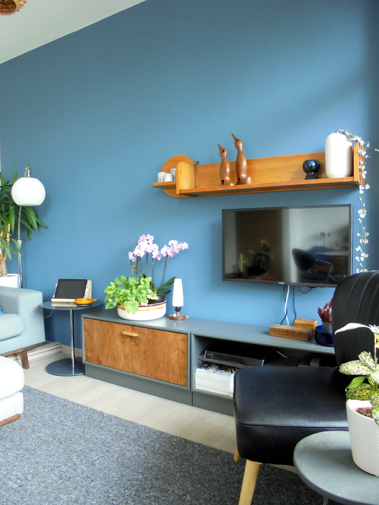 Modelo de salón abierto vintage pequeño con paredes azules y televisor colgado en la pared
