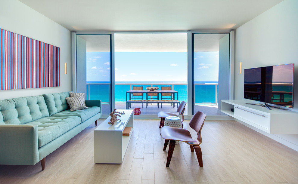 Immagine di un soggiorno design con pareti blu, parquet chiaro, TV autoportante e pavimento beige