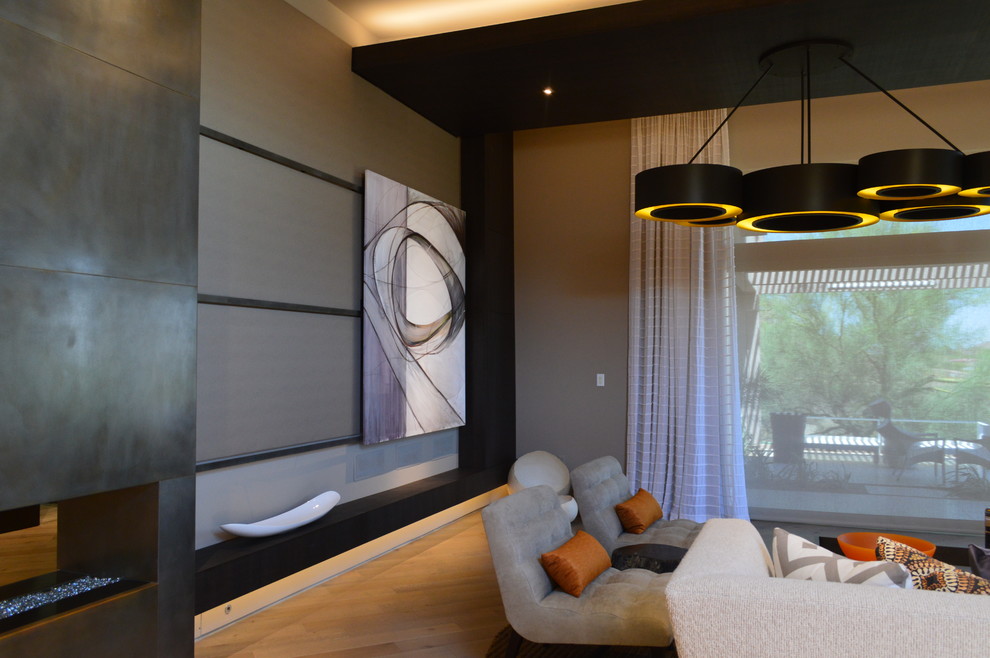 Immagine di un soggiorno design di medie dimensioni e aperto con pareti beige, parquet chiaro, camino bifacciale, cornice del camino in metallo e TV nascosta