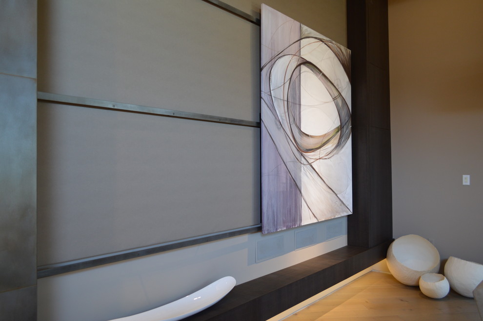 Diseño de salón abierto contemporáneo de tamaño medio con paredes beige, suelo de madera clara, chimenea de doble cara, marco de chimenea de metal y televisor retractable