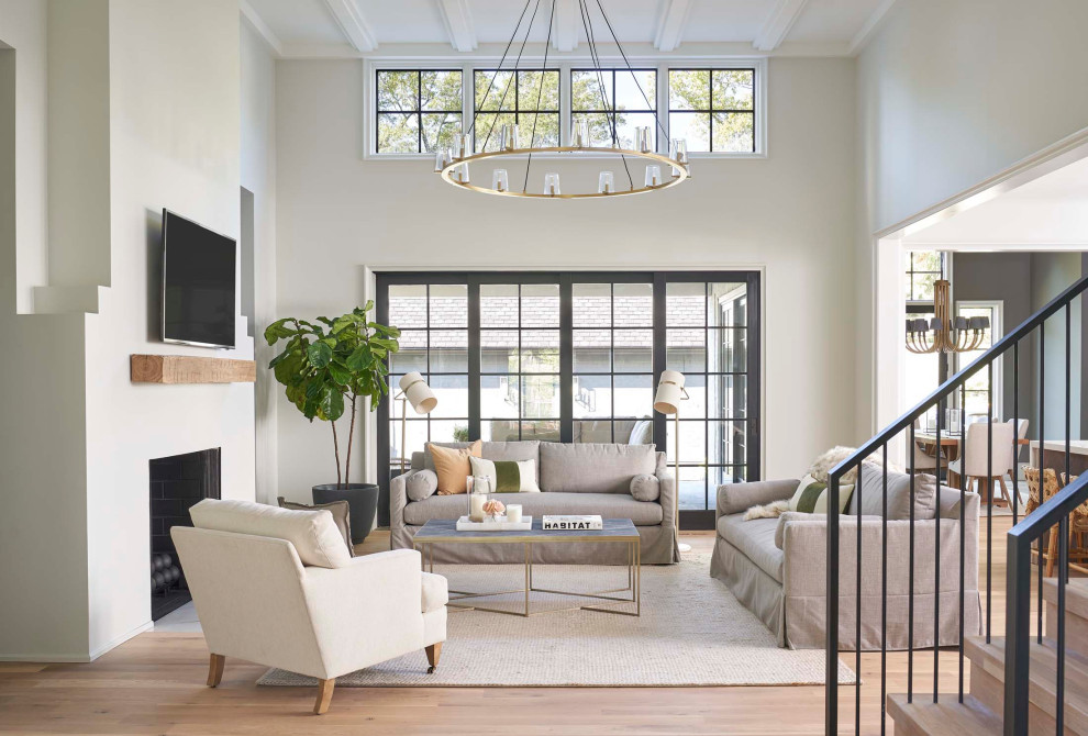 Immagine di un soggiorno classico aperto con pareti grigie, pavimento in legno massello medio, camino classico, TV a parete e pavimento marrone